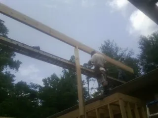 Carpenter setting a ridge beam over a new addition frame — Ice Dam Removal by Roofing Brothers in Pheba