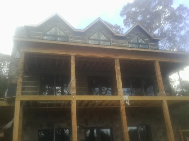 Dormers and porch framing on a large log home under construction — Roof Coating work by our crew in Pheba