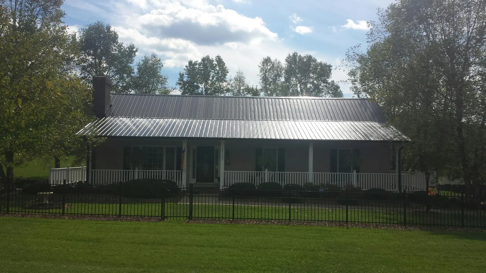 Gray metal roof on a brick ranch with a full width front porch — Gutter Guard Installation work by our crew in Pheba