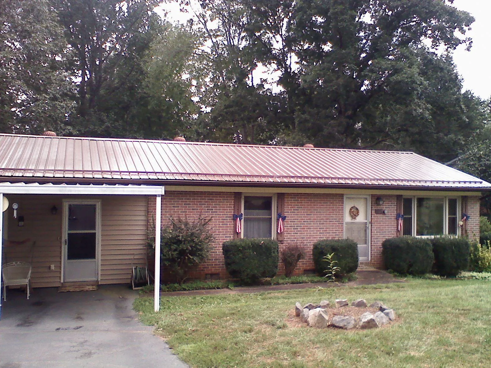 Bronze metal roof and carport on a brick ranch home — Roof Repair work by our crew in Pheba